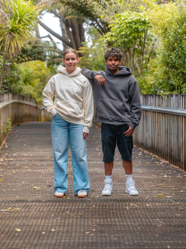 Two friends on a bush boardwalk wearing Pray Hoodies in Peach and Grey